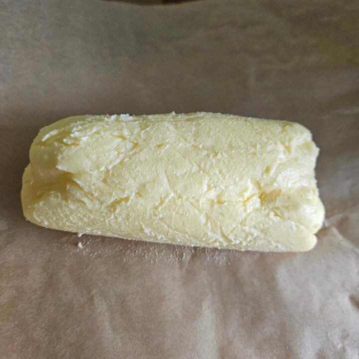 A roll of homemade butter on brown parchment paper.